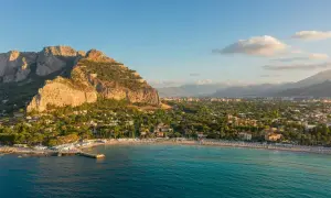 Malowniczy widok na Mondello Beach z turkusową wodą, piaszczystą plażą i górami w tle.