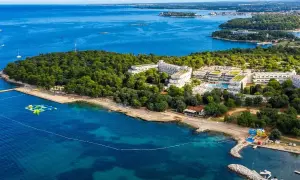 Hotel Delfin Plava Laguna, otoczony zielenią, z basenami i plażą nad turkusowym morzem. Idealne miejsce na wakacje.