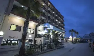 Hotel Canifor Malta o zmierzchu, z palmami i oświetlonymi balkonami.