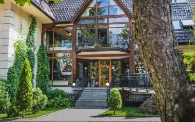 Elegancki hotel Belvedere Resort & Spa z imponującą szklaną fasadą i zielenią wokół.