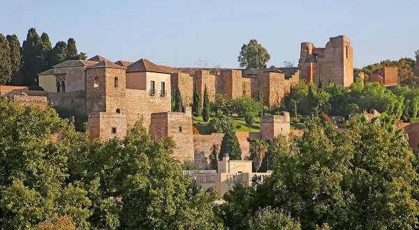 Malaga zamek, starożytna forteca z kamienia, wznosi się na wzgórzu, otoczona zielenią i błękitnym niebem.