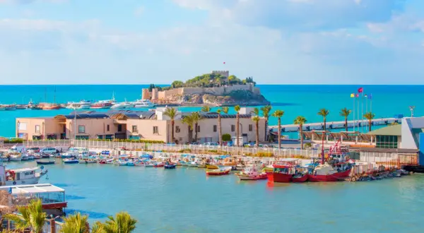 Piękna pogoda w Kusadasi w październiku. Słoneczny dzień nad zatoką pełną łodzi, z widokiem na zamek na wyspie.