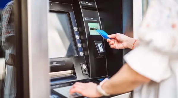 Kobieta dokonuje **revolut wypłata z bankomatu za granicą**. Wkłada kartę do bankomatu, by pobrać gotówkę.