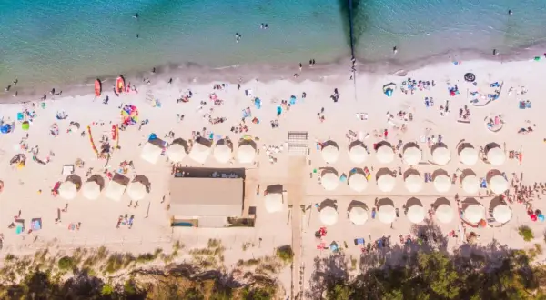 Plaża nad polskim morzem, pełna słońca i ludzi. Idealne miejsce na wakacje all inclusive, gdzie każdy znajdzie coś dla siebie.