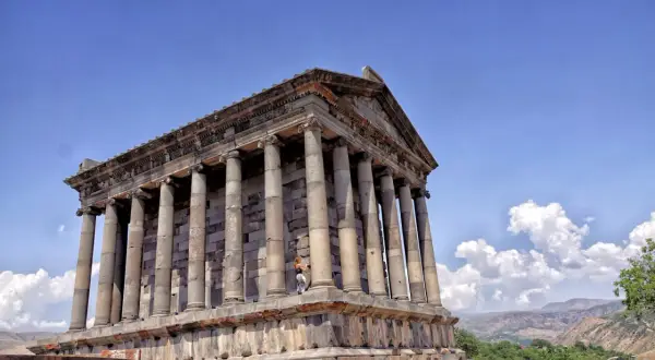 Starożytna świątynia w Garni, symbol bogatej historii i religii Armenii, z turystką na tle kolumn.