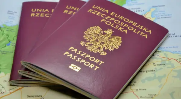 Trzy polskie paszporty leżą na mapie. Dowiedz się, jak wyrobić paszport, by móc podróżować po świecie.