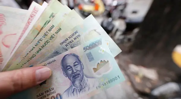 Dłoń trzyma stos banknotów, w tym 500 000 dongów, waluta w Hanoi.