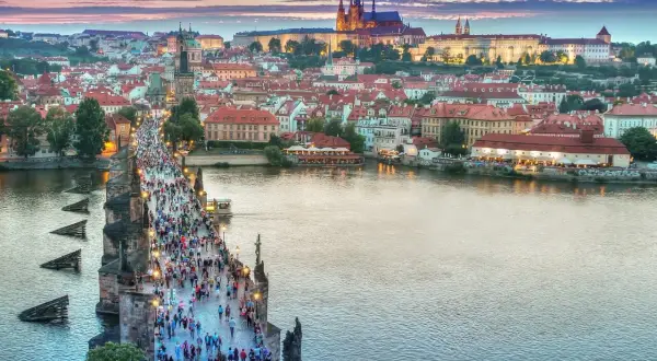 Tłum ludzi na Moście Karola w Pradze, w tle widać Zamek na Hradczanach. Ceny w Czechach mogą być zaskakująco przystępne.