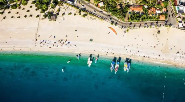 Widok z lotu ptaka na turcja plaże z turystami, łodziami i paralotnią.