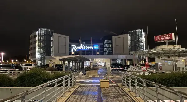Nocny widok na hotel Blu Radisson Hamburg z neonowym napisem i znakiem Turkish Airlines.
