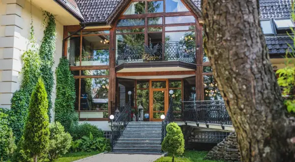 Elegancki hotel Belvedere Resort & Spa z imponującą szklaną fasadą i zielenią wokół.