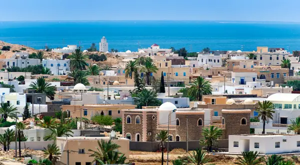 Widok na miasteczko na Djerbie z palmami i morzem w tle. Idealne miejsce, by sprawdzić, jaka jest djerba temperatura wody.