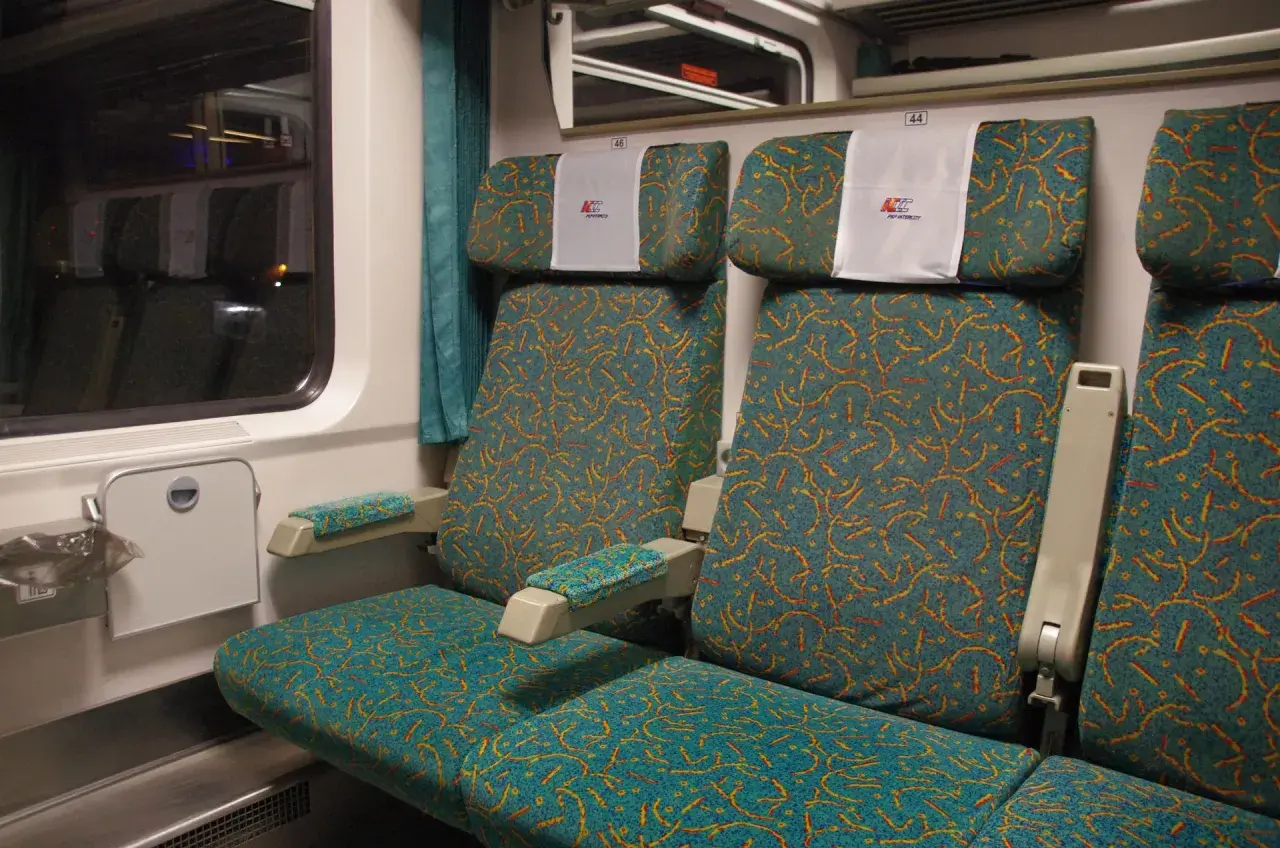 Wygodne siedzenia w wagonie bezprzedziałowym PKP Intercity. Wzór na tapicerce przypomina falujące linie.
