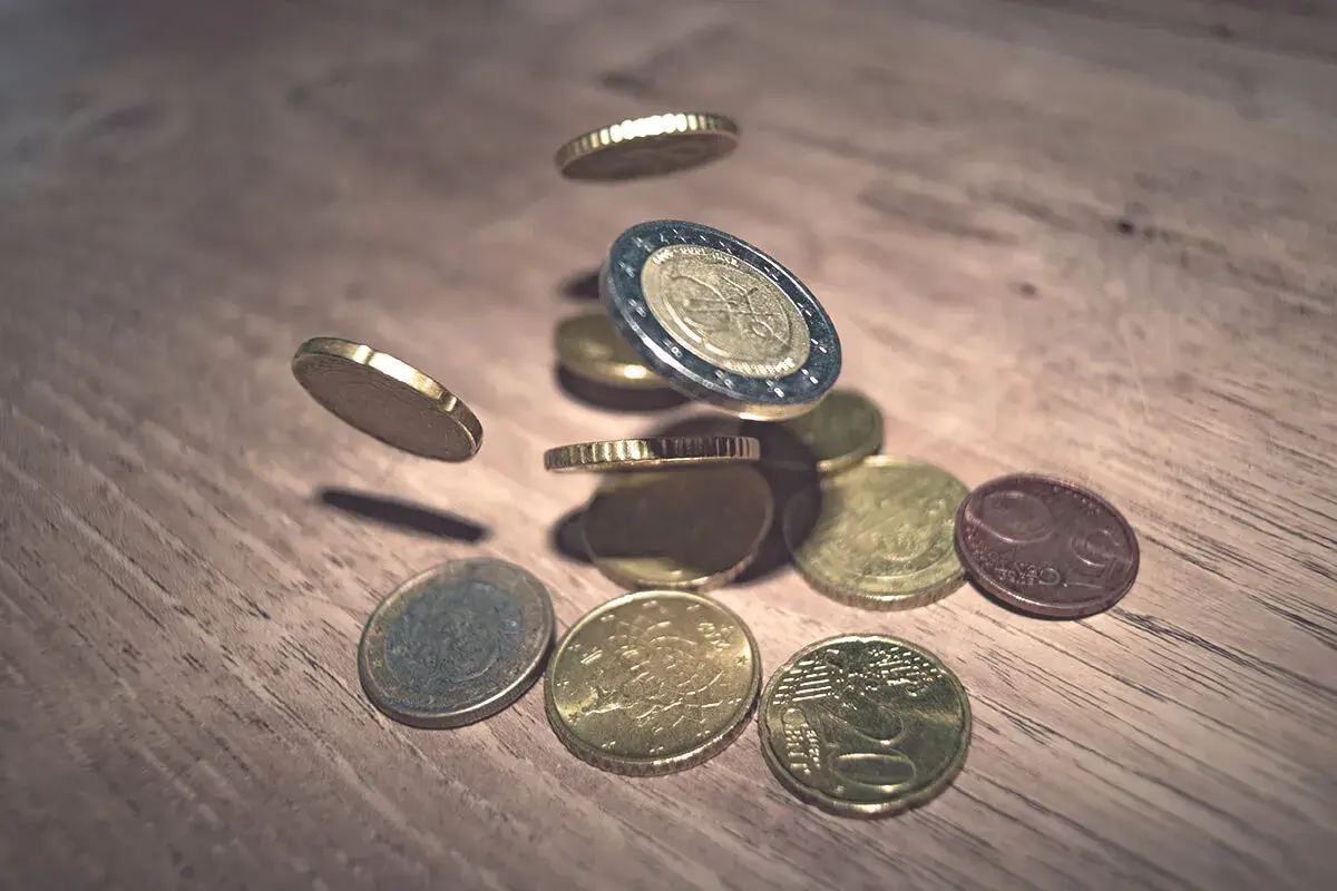 Monety euro spadające na drewniany blat. To waluta Hiszpanii, symbolizująca bogactwo i handel.