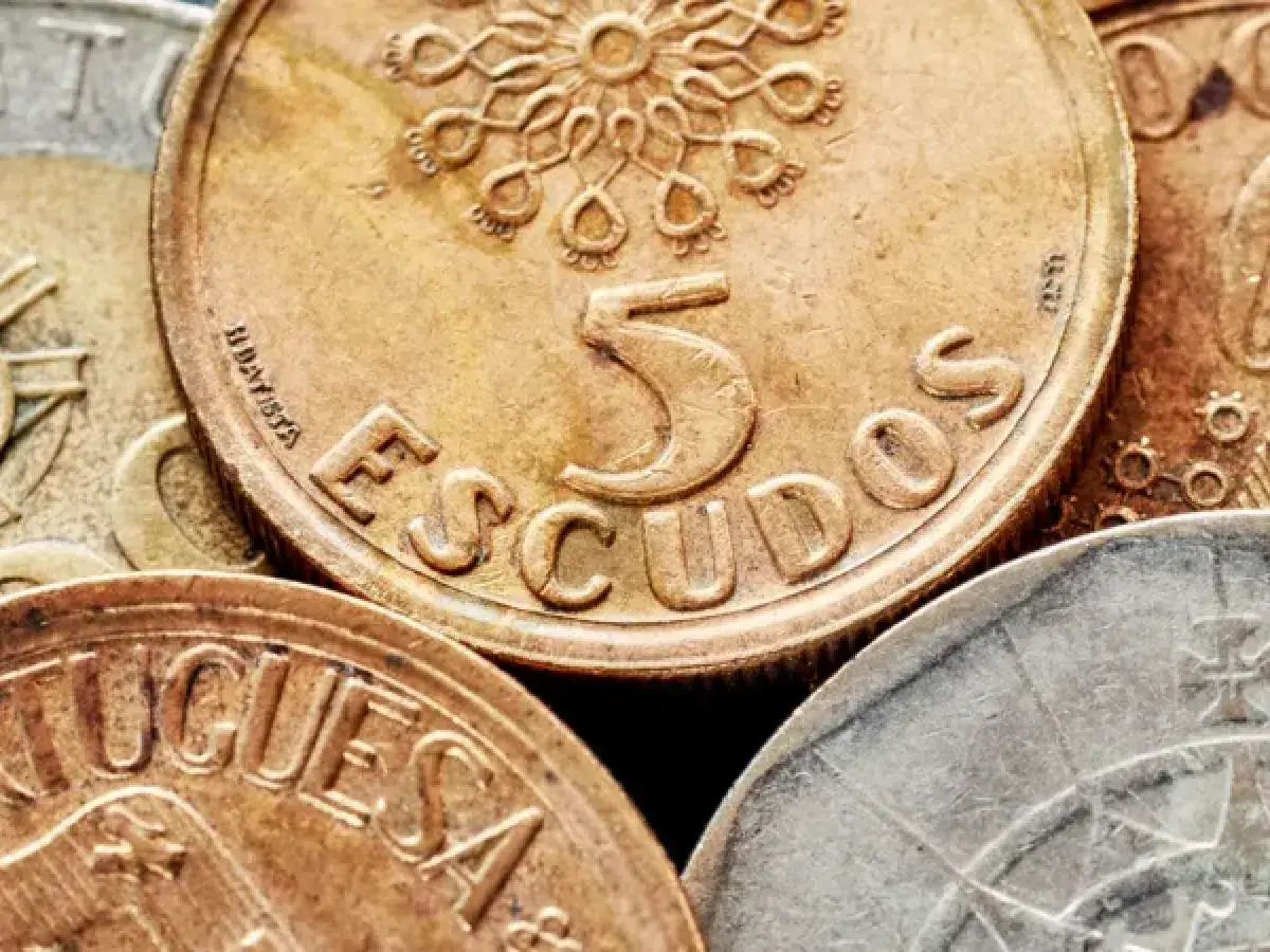 Złote monety z napisem "ESCUDOS" i cyfrą 5, dawna waluta Portugalii przed euro.