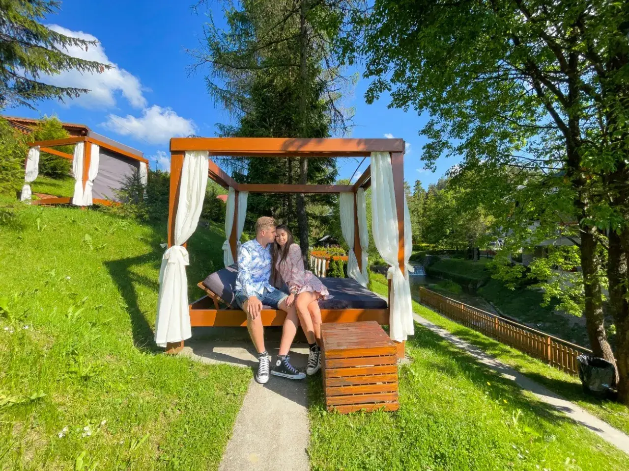 Para spędza romantyczny last minute weekend dla dwojga na łóżku pod baldachimem, otoczona zielenią i strumykiem.