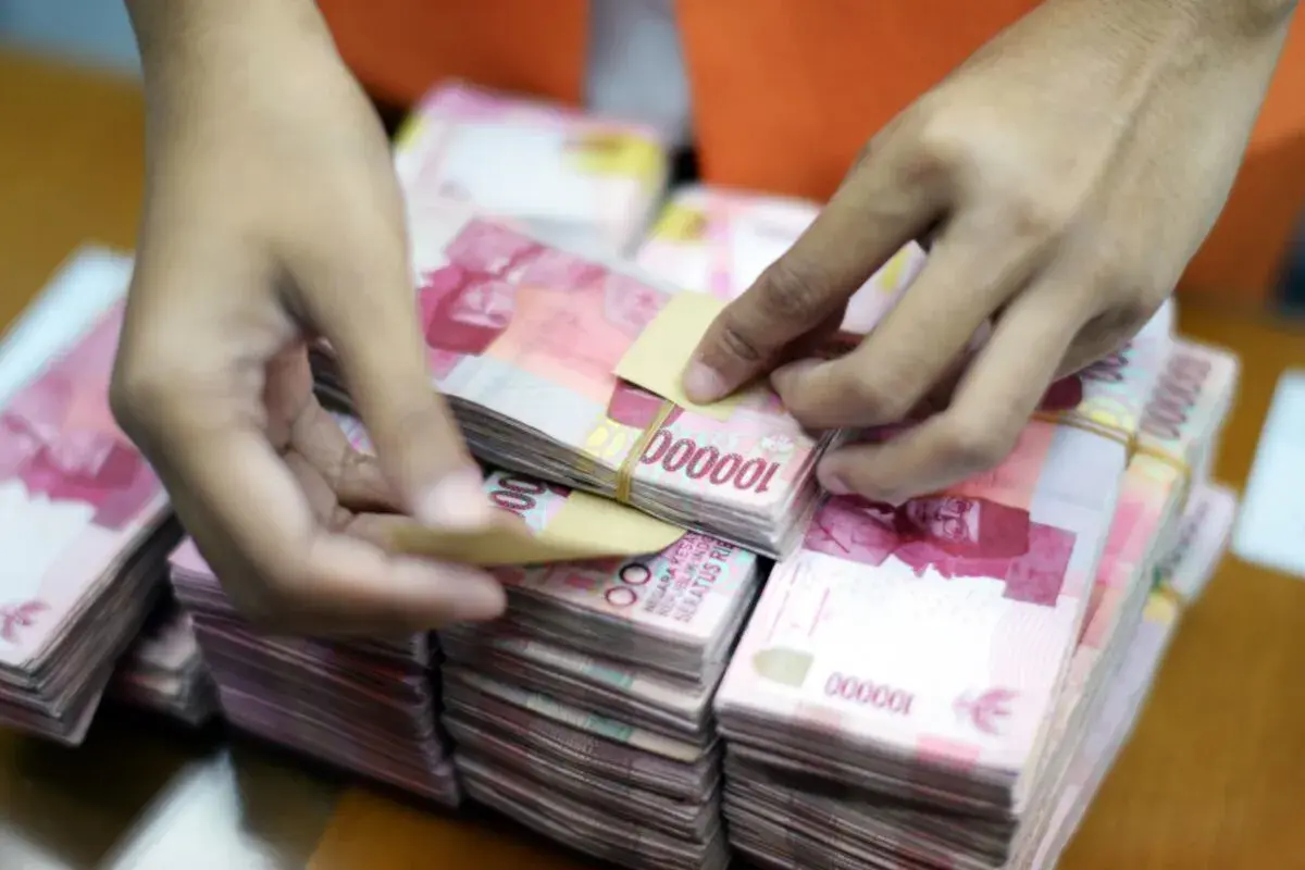Ręce liczą stosy banknotów 100 000 rupii, waluta Indonezji.
