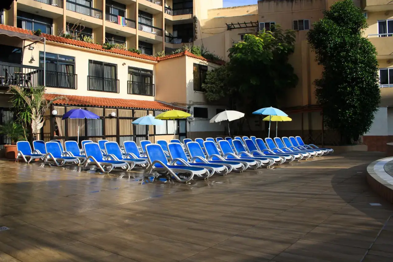 Rzędy leżaków i parasoli przy basenie hotelu Canifor Malta.