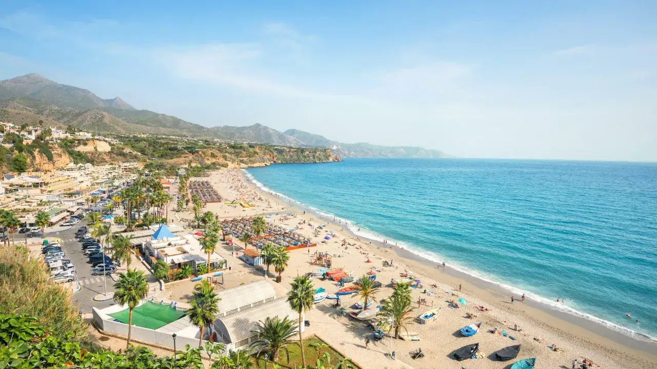 Malaga temperatura styczeń: słoneczna plaża z palmami i turkusowym morzem, idealna na zimowy wypoczynek.